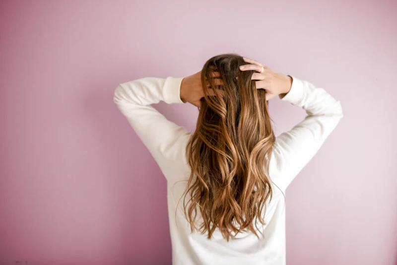 Cliente mostrando o cabelo ondulado e brilhoso depois do atendimento