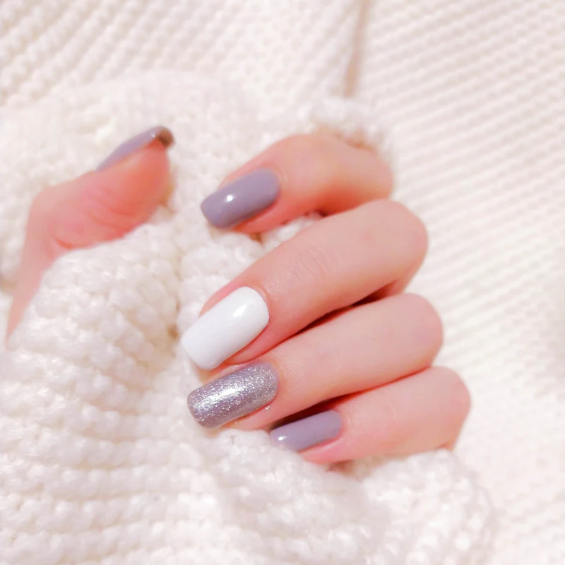 Mãos com unhas pintadas em tons de lilás e branco